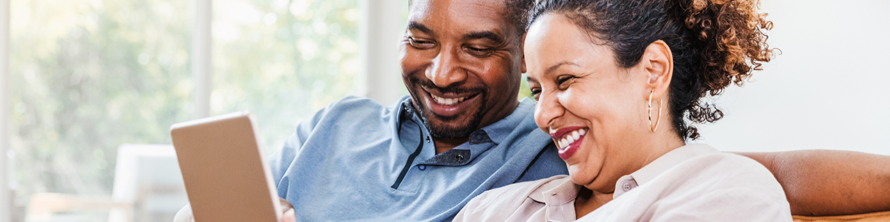 Couple on their sofa smiling at tablet