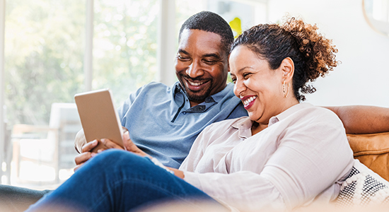 Couple on their sofa smiling at tablet