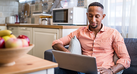 Man sitting on sofa looking at laptop